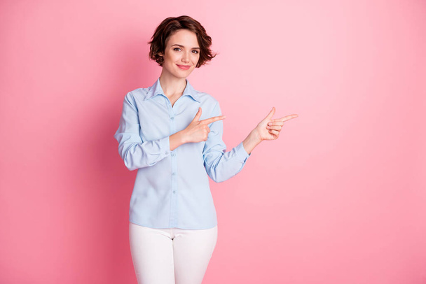 Photo of attractive charming pretty lady direct fingers side empty space show sale discount banner shopper wear blue office shirt white pants isolated pink pastel color background - Fotografie, Obrázek