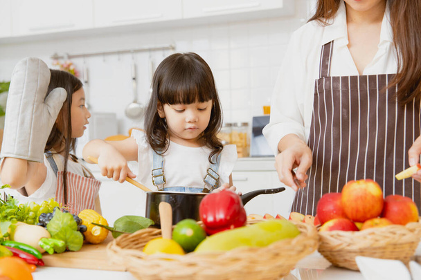 Niña niños disfrutan jugando a la cocina con mamá y hermana mayor juntos en casa vacaciones de cocina - Foto, imagen