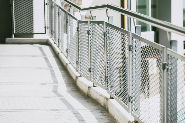 Sendero de aceras con vallas metálicas y asas de acero inoxidable para caminar con seguridad en estilo urbano moderno. - Foto, imagen