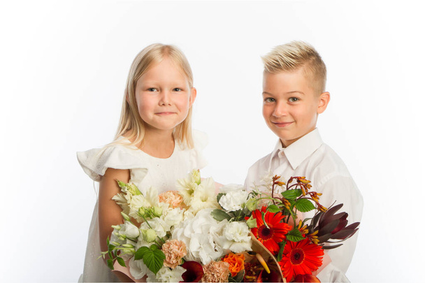 Studio portrait boy gives girl festive bouquet, congratulatory concept, white backdrop, copy space - Photo, Image