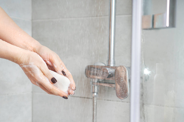 Mädchen waschen sich in einer Duschkabine die Hände mit Seife. Wellness- und Entspannungsanwendungen zu Hause.  - Foto, Bild