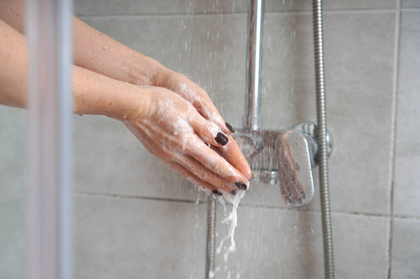 Hands hygiene. Washing hands with soap in a shower cabin. Washing off the foam. - Foto, Bild