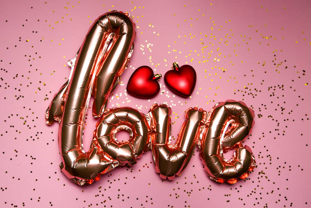 golden word love with red hearts on pink background - Photo, Image