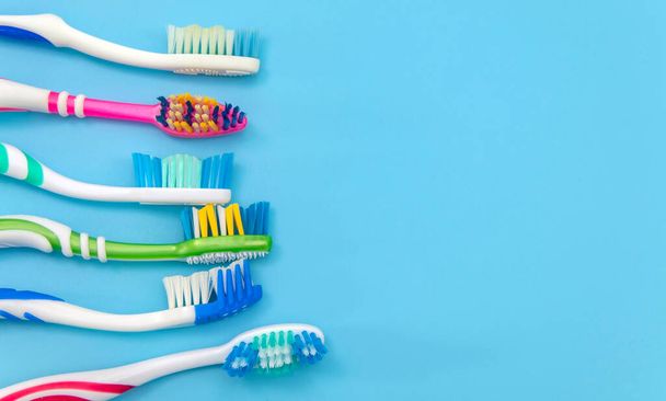 Πολύχρωμες οδοντόβουρτσες σε έγχρωμο φόντο με χώρο αντιγραφής. Άποψη από ψηλά - Φωτογραφία, εικόνα