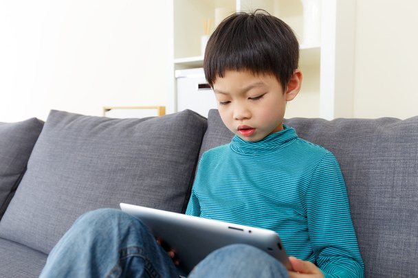 Asiático pequeño niño concentrado en tableta en casa
 - Foto, imagen