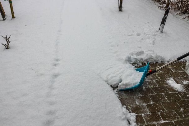 Вид человека, убирающего снег на аллее лопатой. Концепция зимнего сезона. - Фото, изображение