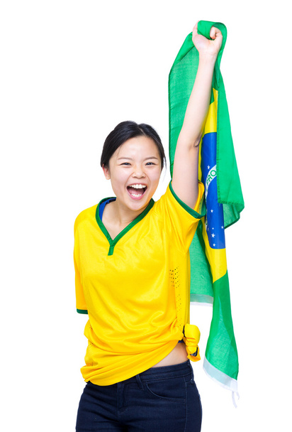 ασιατική γυναίκα με κίτρινο ποδόσφαιρο ρούχα και κρατήσει ψηλά τη σημαία της Βραζιλίας - Φωτογραφία, εικόνα