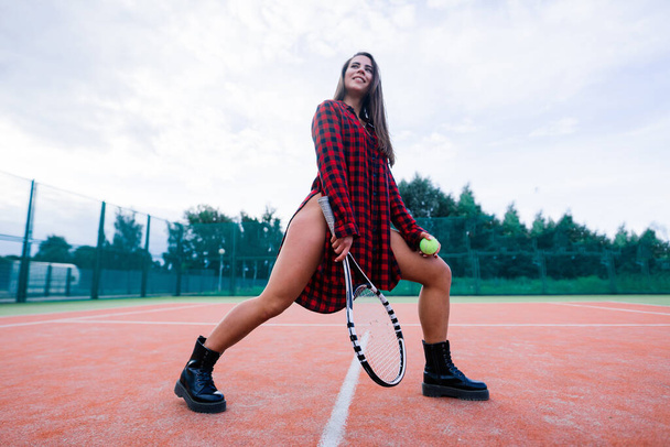 Schöne stilvolle sexy Frau in einer schwarzen trendigen Sportbekleidung auf dem Tennisplatz. - Foto, Bild