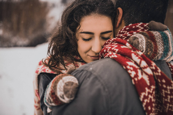 Молодой человек и женщина стоят, целуясь и обнимаясь. Невеста и жених влюблены пара в вязаный шарф и варежки зимой со снегом и снежинками. свадебное платье. Персоналии: Мексика - Фото, изображение