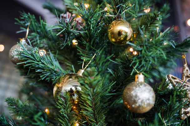 Golden star on the Christmas tree, Christmas tree decoration with Golden balls garland, green spruce in the interior of the apartment, preparation for the Christmas holiday - Foto, afbeelding