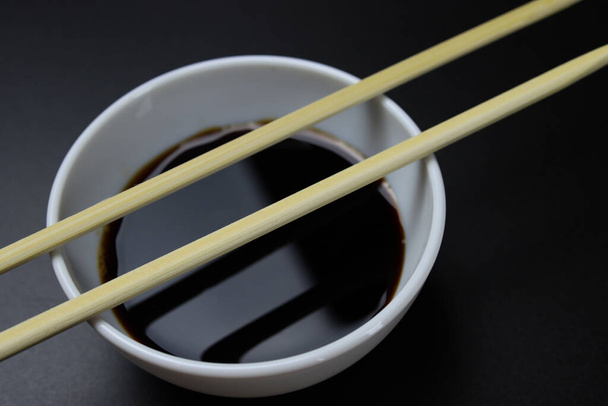 Деревянные палочки для еды, суши на кастрюле с соусом - Фото, изображение