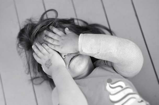 Pahoinpidelty tyttö, jonka käsi on murtunut.
 - Valokuva, kuva