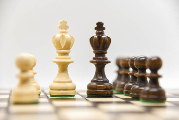 Black and white wooden figures for chess on the board - Photo, Image