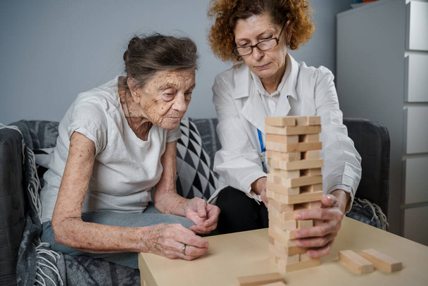 成熟した医師によるセッション、老人ホームでの高齢者のための治療、認知症のための細かい運動能力の訓練、アルツハイマー病や木製のブロックを折り畳むことによって回復研究所、 jengaを再生. - 写真・画像