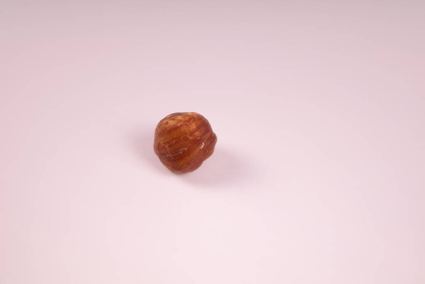 One peeled kernel of ripe hazelnut on a white background - Valokuva, kuva