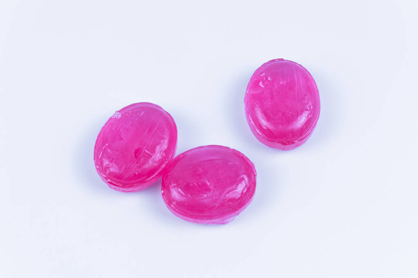 Tres caramelos del mismo color rosa sobre un fondo blanco - Foto, Imagen