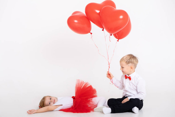 niño pequeño dando globos de corazón a niña en el día de San Valentín sobre fondo blanco - Foto, Imagen