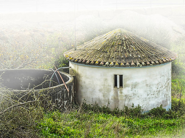 Αγροτικό κτίριο με στέγη σε σχήμα κώνου στην ομίχλη - Φωτογραφία, εικόνα
