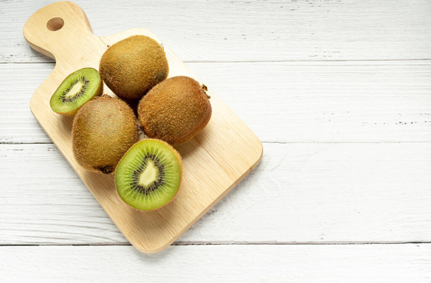 Rijp hele kiwi 's en halve kiwi' s op houten snijplank. Volledige scherptediepte. veganistisch voedselconcept - Foto, afbeelding