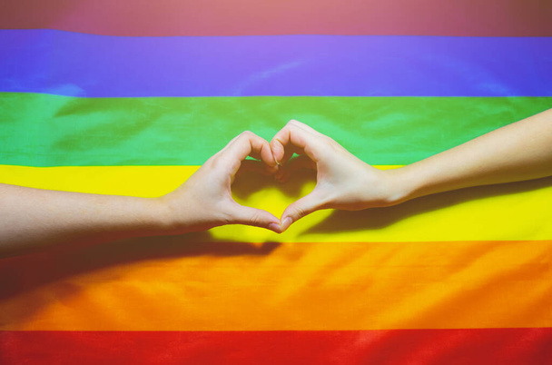 Lgbt community colorful flag. Two women's hands on rainbow background. Lesbian and gay problems. Legalization of marriage for couples with homosexual orientation. - Fotó, kép