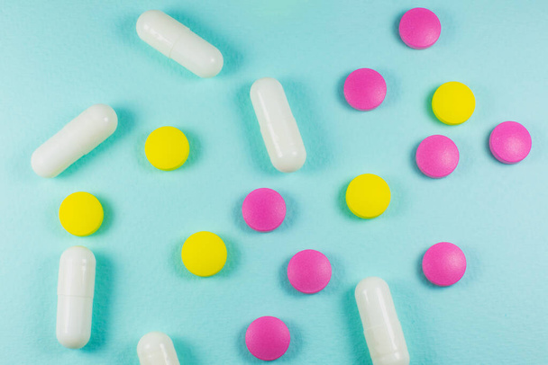 Colored pills and tablets on green background. Close up. Medical treatment concept. - Fotografie, Obrázek