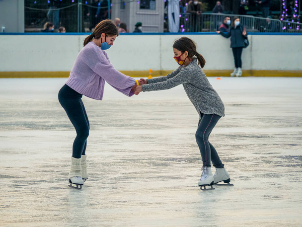 Bucarest Roumanie - 12.25.2020 : Deux jeunes filles patinent sur la patinoire du parc Cismigiu, à Bucarest - Photo, image
