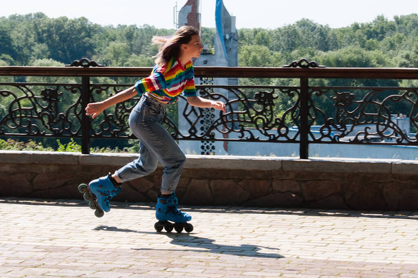Cheerful beautiful teenage girl rollerblading in the park on awarm summer morning - 写真・画像