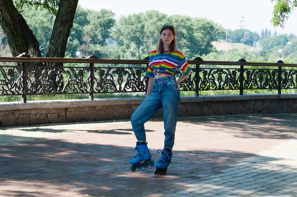 Привлекательная девушка-подросток на роликовых коньках в солнечный летний день позирует в парке - Фото, изображение