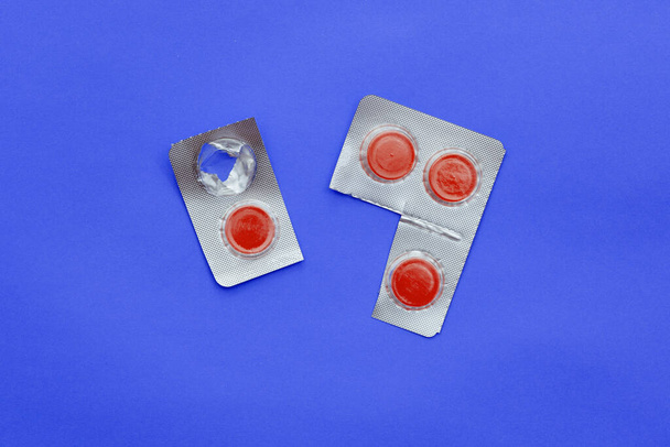 Red pills in packaging on a colored background. Pain medicine. Antibiotics for the treatment of infections and diseases. Medicines, pharmaceuticals. - Photo, Image