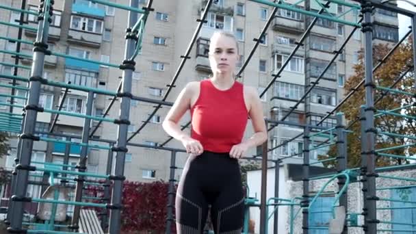 Porträt einer jungen, durchtrainierten blonden, vollbusigen Frau mit Pferdeschwanz, die auf einem Sportplatz steht - Filmmaterial, Video