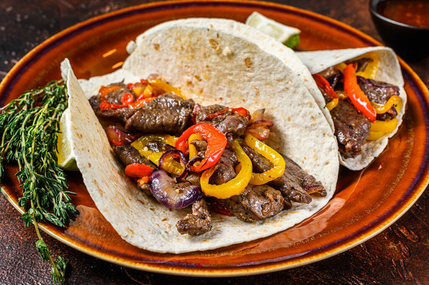 Fajitas Tortilla wraps with beef meat steak stripes, sweet pepper and onions. Dark Wooden background. Top view. - Photo, Image