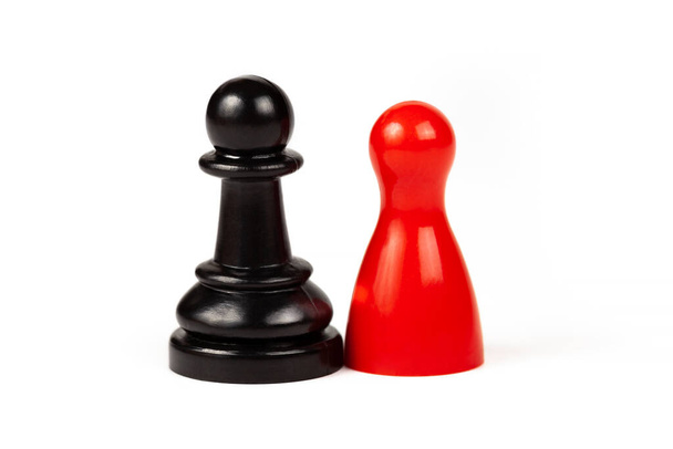 Diferencias emparejadas concepto de unión, dos piezas. Pieza de juego roja y un peón de ajedrez negro de pie juntos, aislados en blanco, cortados. Diversidad, tolerancia, diálogo y amistad concepto abstracto - Foto, imagen