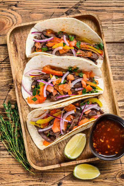 Tacos mit Rindfleisch, Zwiebeln, Tomaten, Paprika und Salsa. Mexikanisches Essen. Holzuntergrund. Ansicht von oben. - Foto, Bild