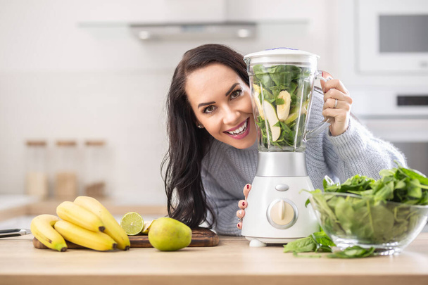 Vitamins packed blender ready to be mixed into a smoothie by a beautiful woman. - Foto, Imagem