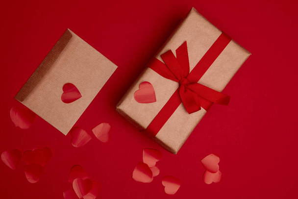 Valentine day composition. Confetti, envelope postcard with heart on red background - Fotografie, Obrázek