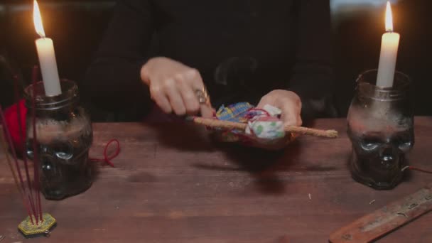 Nahaufnahme einer Wahrsagerin, die in einem schrecklichen magischen Ritual eine Nadel in eine Voodoo-Puppe steckt - Filmmaterial, Video