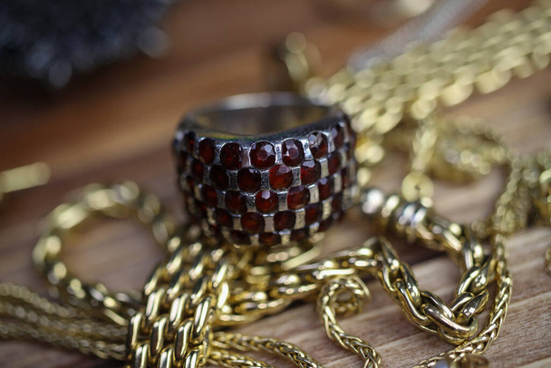 Close up isolated group gold precious jewellery chains and bracelets with silver ruby gem ring on wood table - Foto, Bild