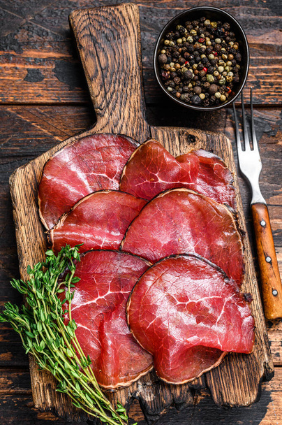 Antipasti Bresaola italien salé morceaux de viande de bœuf coupés. Fond en bois foncé. Vue du dessus. - Photo, image