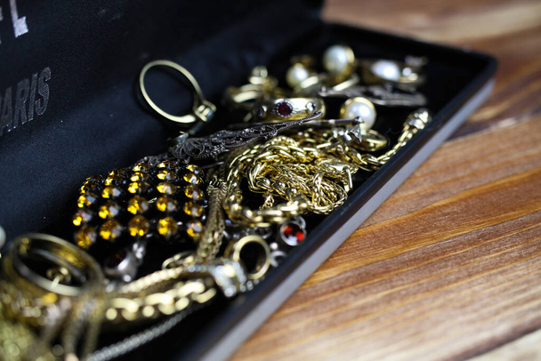 Close up of isolated jewellery box with gold and silver jewel pieces on wood table - Foto, Imagem