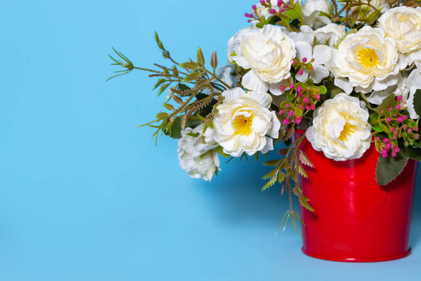 flowers for interior decoration in a red pot on a blue background. - Zdjęcie, obraz