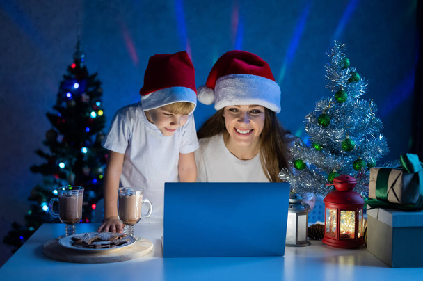 Happy mom and son talking on a video call on a laptop on christmas night. - Zdjęcie, obraz
