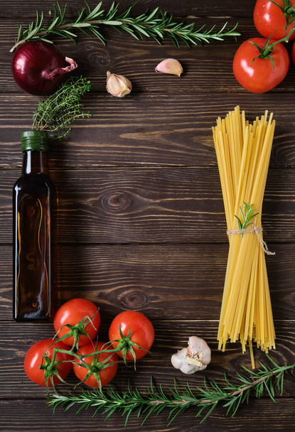 Спагетті з інгредієнтами на сільському дерев'яному столі. Ціла зернова паста на сільському темному дерев'яному столі - підготовка обіду в італійському стилі. Простір рецепта в центрі рамки, вид зверху
 - Фото, зображення