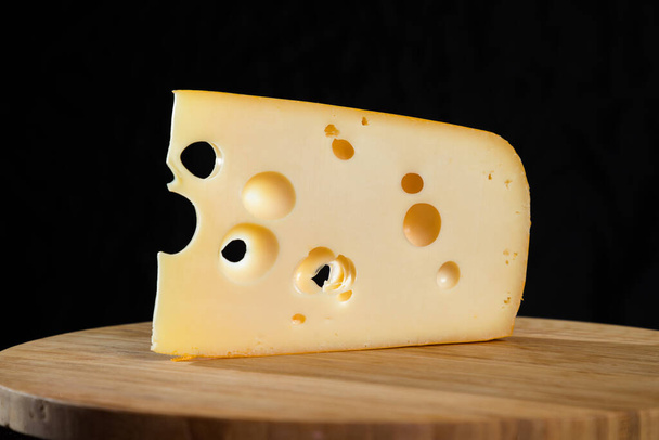 Tahtada delikleri olan sarı inek sütü İsviçre peyniri. - Fotoğraf, Görsel