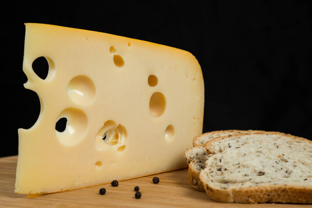Κίτρινο αγελαδινό γάλα Ελβετικό τυρί emmenthal με τρύπες στον ξύλινο πίνακα - Φωτογραφία, εικόνα