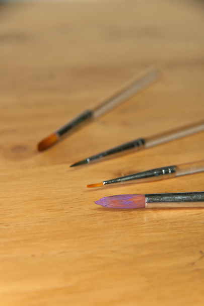 Різні розміри пензлів на дерев'яному фоні
 - Фото, зображення