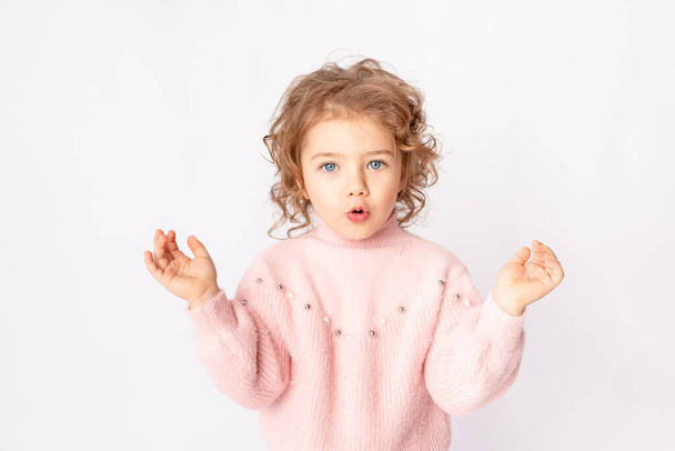 surprised baby girl in pink winter clothes on white background, space for text - Фото, изображение