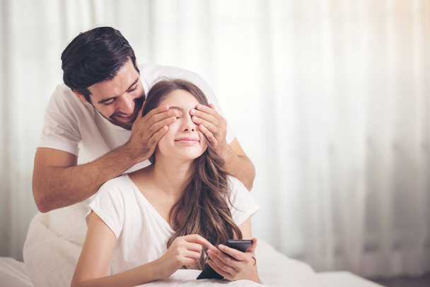Young couple in bed, Happy smiling couple lying covered with blanket and Mobile Phone - Foto, imagen
