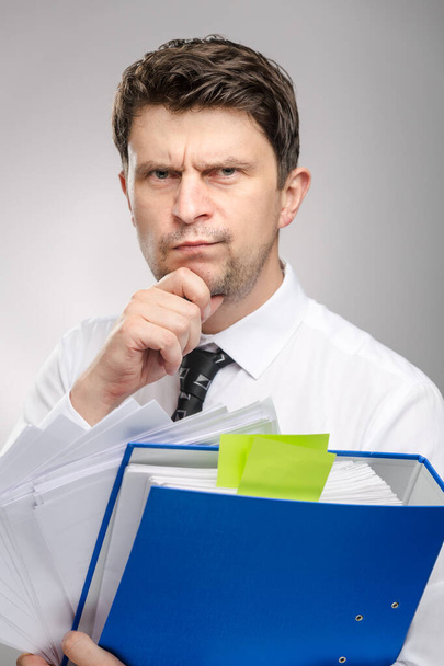 Man with lot of documents, worker of the month with thinking face expression. Office clerk in white shirt preparing for a presentation. - Foto, imagen