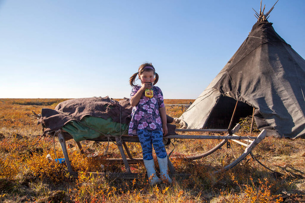 El extremo norte, Yamal, el pasado de la gente Nenets, la vivienda de los pueblos del norte, una niña jugando cerca de las yurtas en la tundra. - Foto, imagen