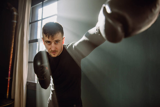 The man is an athlete boxing in the gym. Boxer practicing punches in the ring. Shadow-boxing. The athlete strikes with a punching bag. 4k video - Fotó, kép